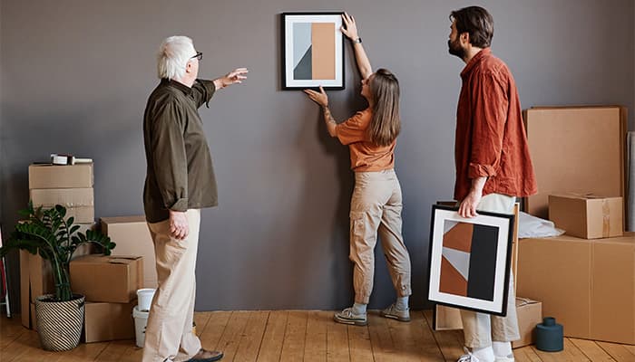 Young lady hanging artwork while being given direction