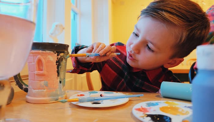 Child painting pottery at Potters Barn