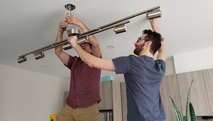 Two men removing a light fixture