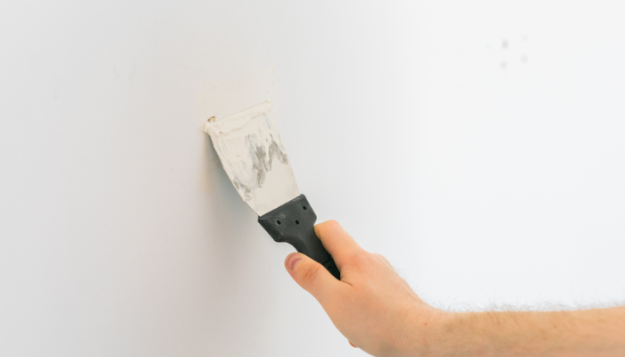 Patching up holes in the wall with filler